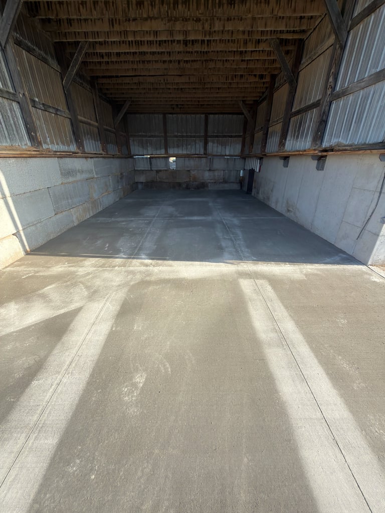 Interior view of empty agricultural warehouse or storage barn with open double doors and concrete floor